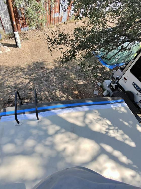 Blue masking tape run along the drip edge of an RV roof
